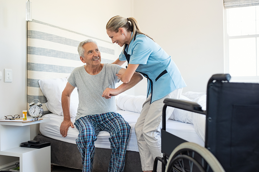 caregiver helping elderly man out of bed