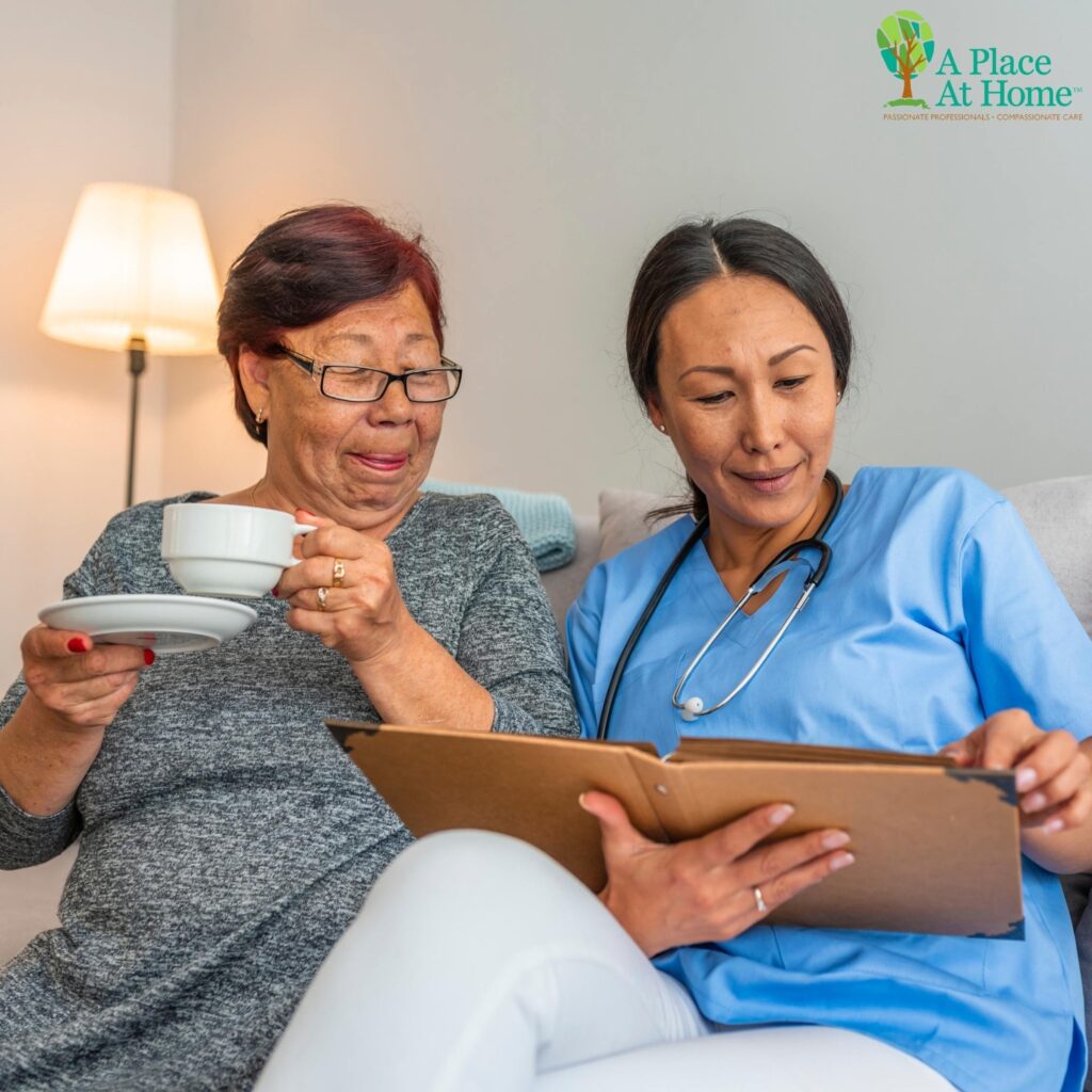 A Place at Home Carrollton caregiver drinking tea with senior woman and sharing old memories