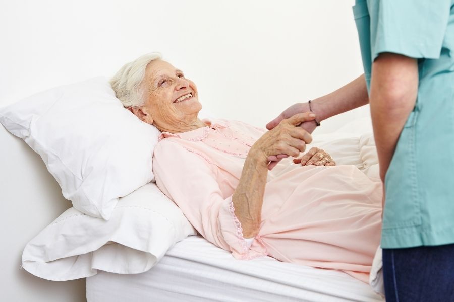 Caregiver putting senior woman to bed a part of overnight care