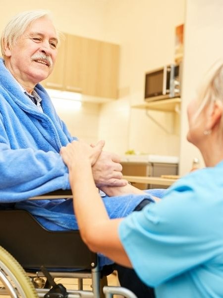 Caregiver helping a senior man with daily activities at home