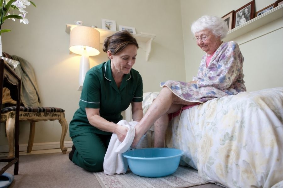 caregiver giving bed bath to senior