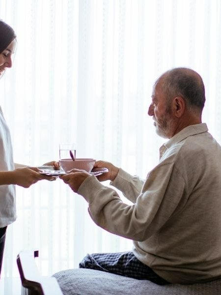 Respite caregiver serving a meal to a senior man