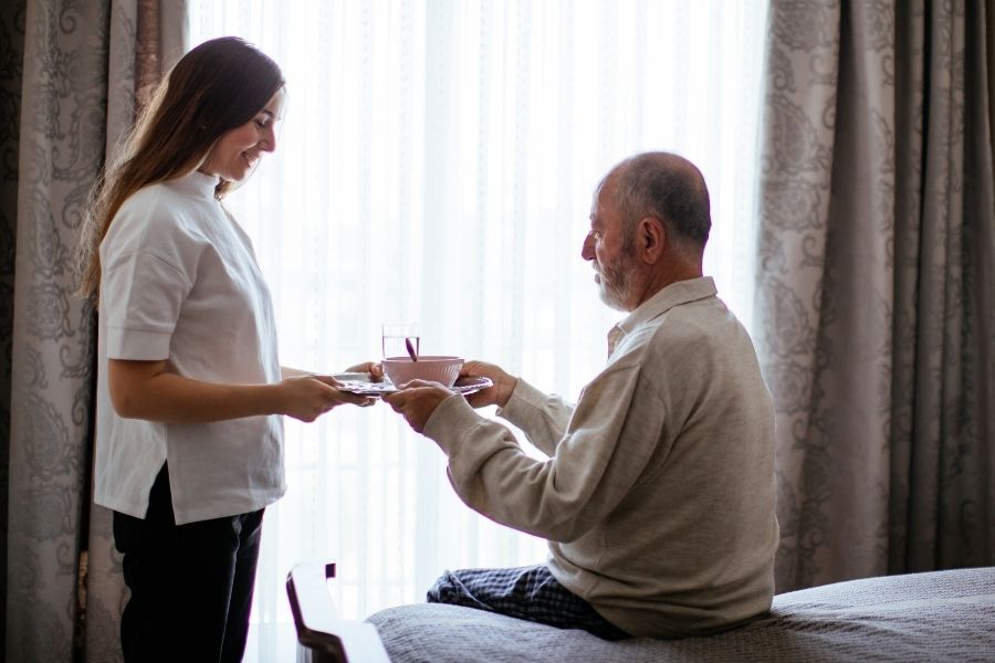 caregiver giving meals to senior as a part of live in care