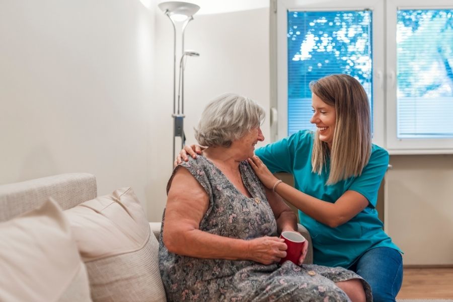 A caregiver sitting with Senior on sofa