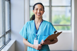 Smiling Medical Professional in Scrubs Holding a Clipboard in Hospital Setting