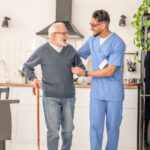 A caregiving helping an elderly man walk