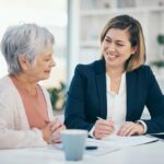 An elderly woman speaking with a younger woman