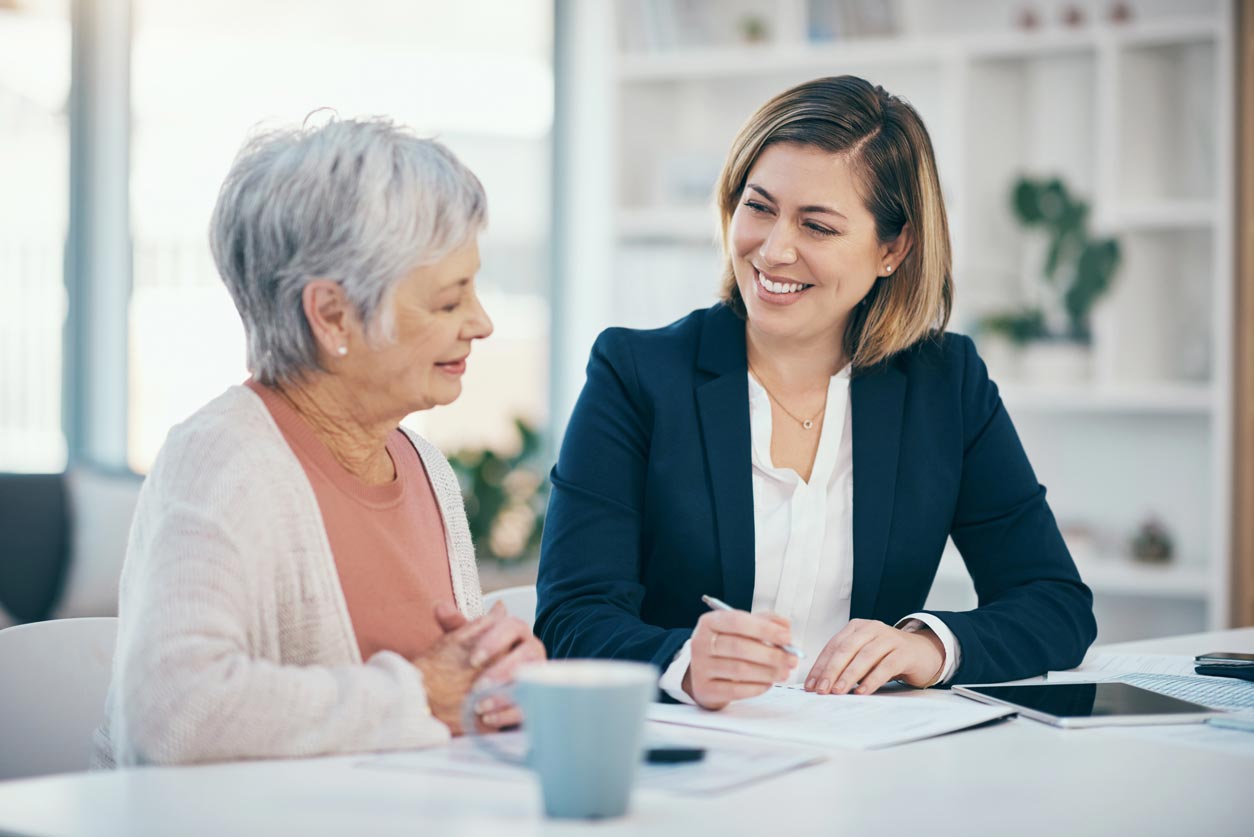An elderly woman speaking with a younger woman