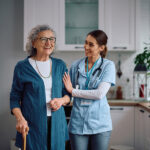 A caregiver helps an elderly woman walk
