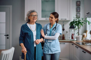 A caregiver helps an elderly woman walk