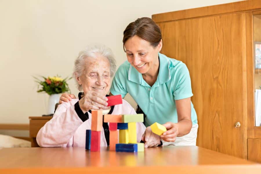 Dementia Caregiver Assisting Senior woman with a mind game to keep her active