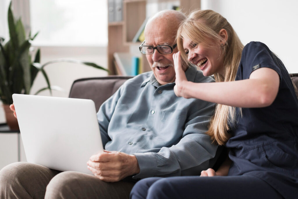 caregiver and elderly man using computer