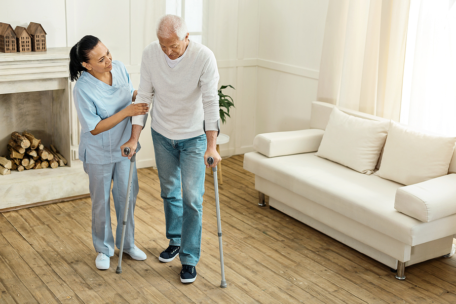 Caregiver helping elderly man walk