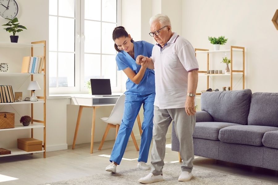Caregiver holding a senior man's hand to help prevent a fall in Los Alamitos, CA
