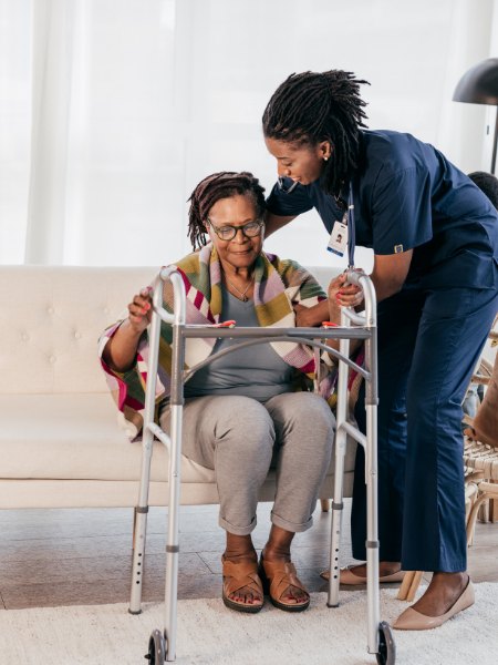 Caregiver helping a senior walk safely with a walker at home in Los Alamitos, CA