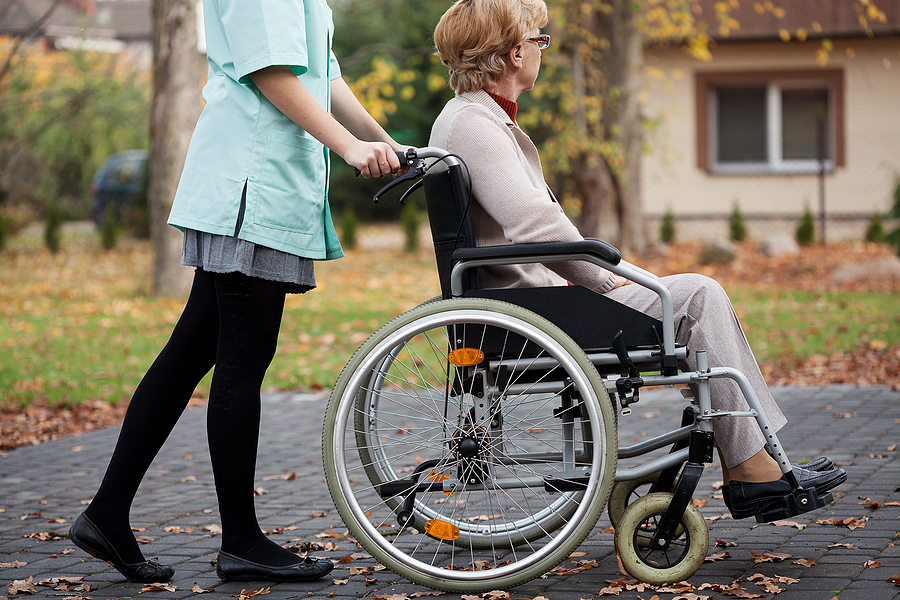 Caregiver on a relaxing walk with elder woman on wheelchair