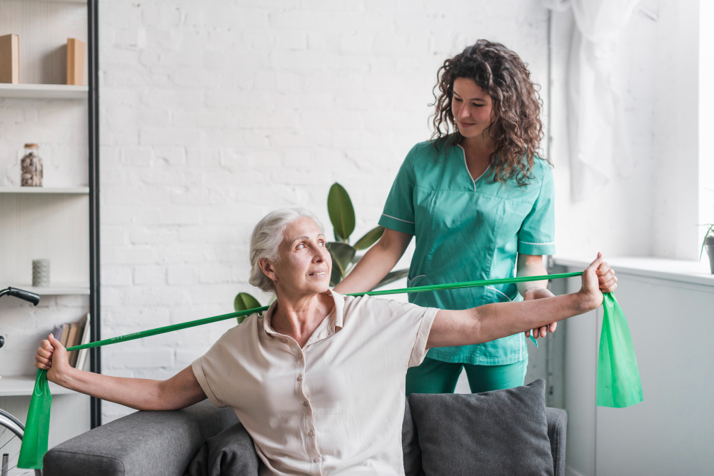 Caregiver helping elderly woman stretch with exercise band