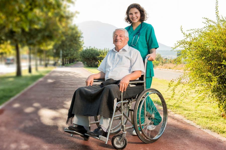 Caregiver assisting elderly man in wheelchair