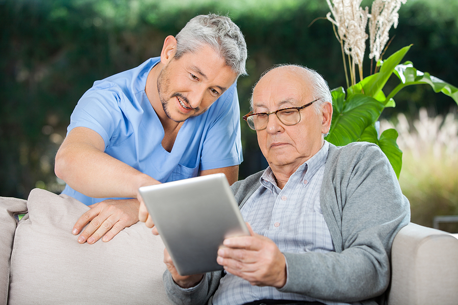 elderly man and caregiver reading something on a digital tablet