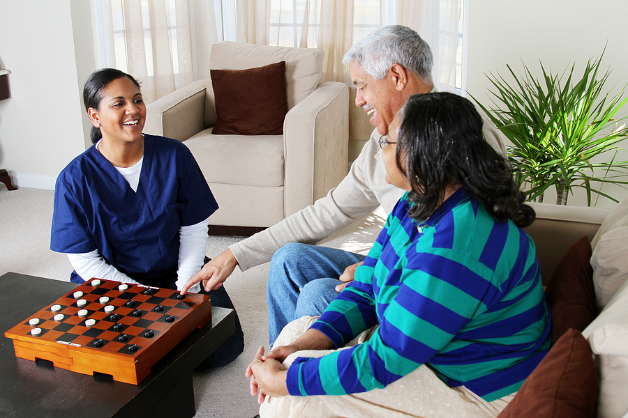 caregiver playing chess with elderly couple