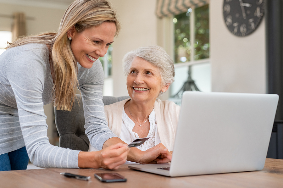 caregiver and elderly woman working on a laptop