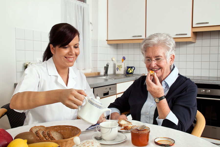 Elderly woman and caregiver enjoying breakfast