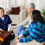 caregiver playing chess with elderly couple