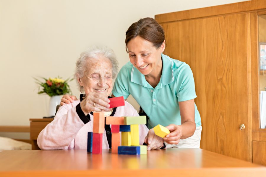 Dementia Caregiver Assisting Senior woman with a mind game to keep her active