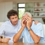a young man consoling his senior father who is dealing with anxiety and stress