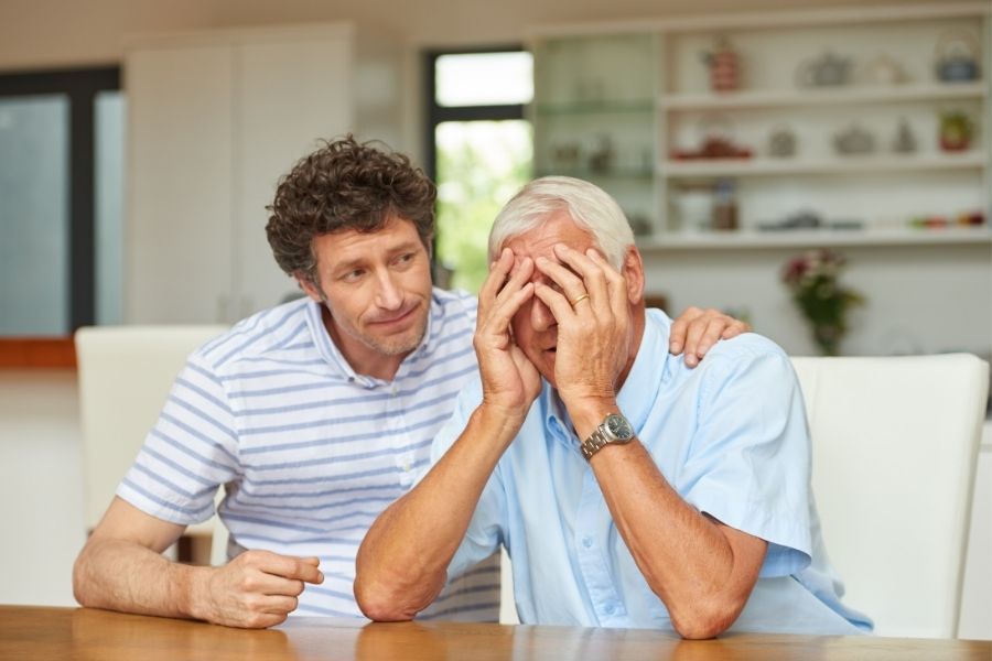a young man consoling his senior father who is dealing with anxiety and stress