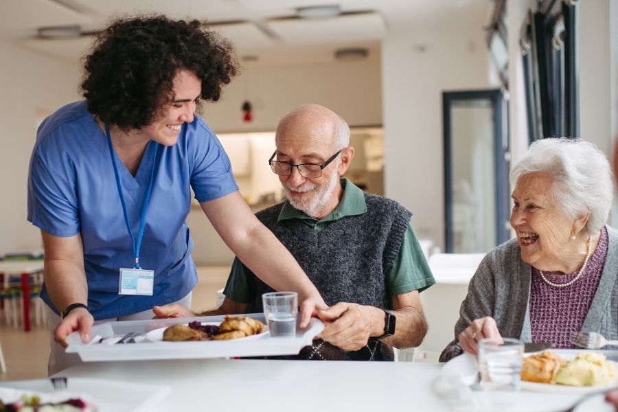 caregiver giving meals to senior couples as a part of care at home services