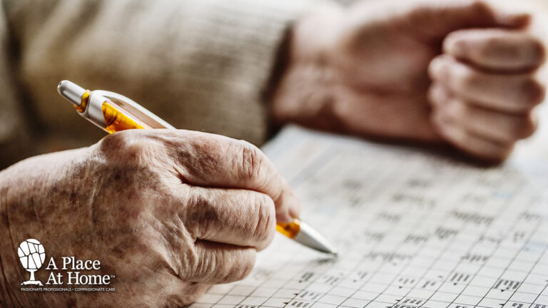 A shot of a senior's hands filling out a chart with a pen.