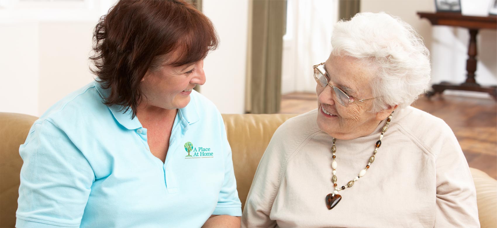 A caregiver from A Place At Home speaks to a senior woman she is assisting.