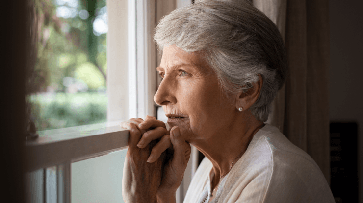 Risks of Loneliness in Seniors senior woman looking out window alone