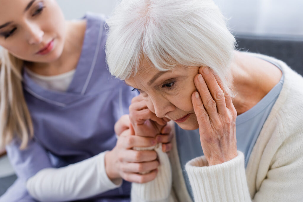 Caregiver comforting distressed elderly woman