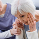 Caregiver comforting distressed elderly woman