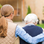 Caregiver holding onto elderly woman's shoulders