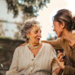 Older woman talking to a younger woman on a park bench